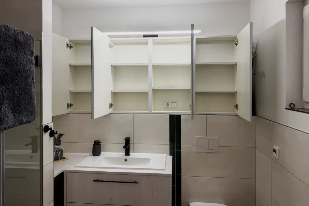 Offener Hängeschrank mit Einlegeböden über Waschtisch im modernen Bad, mit Fliesenwand und Armatur.