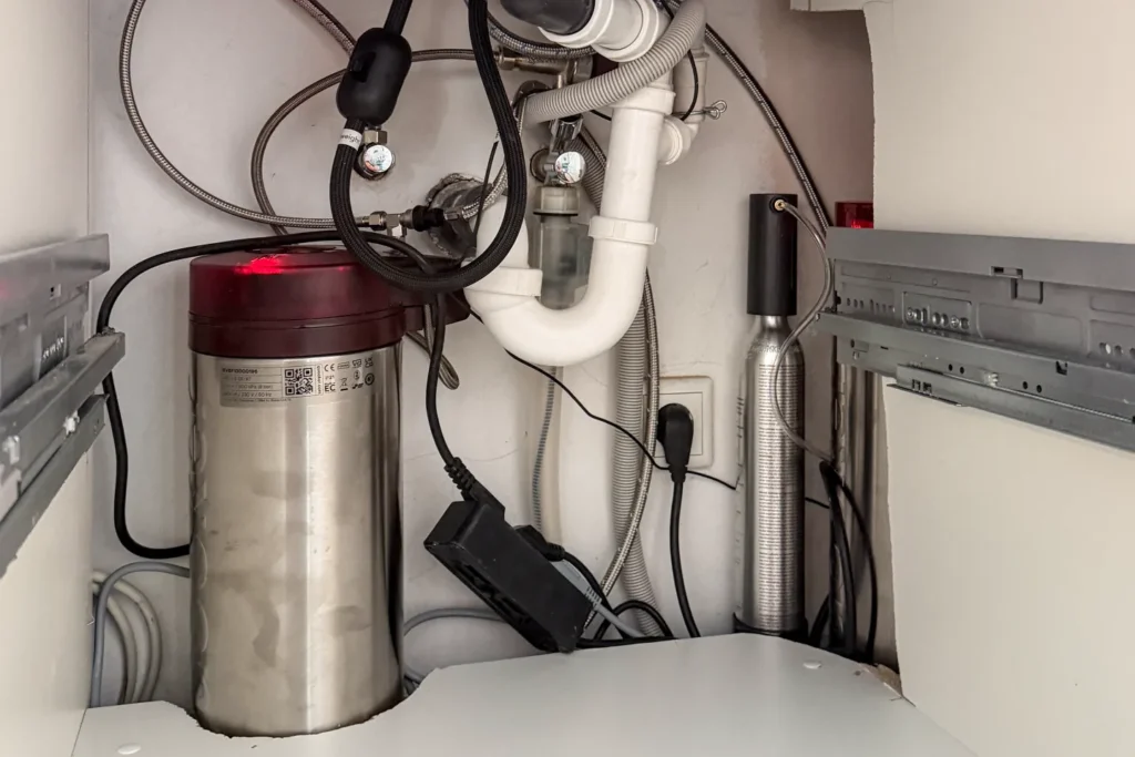 Küchenunterschrank mit Edelstahl-Wasserfilter, Leitungen und Ventilen im Innenbereich