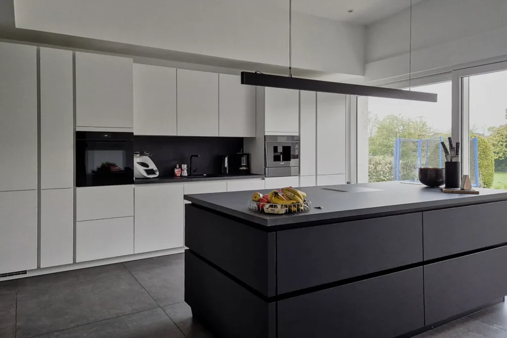 Moderne Küche mit weißen Fronten, dunkler Kücheninsel, integrierten Geräten und Hängelampe über der Insel
