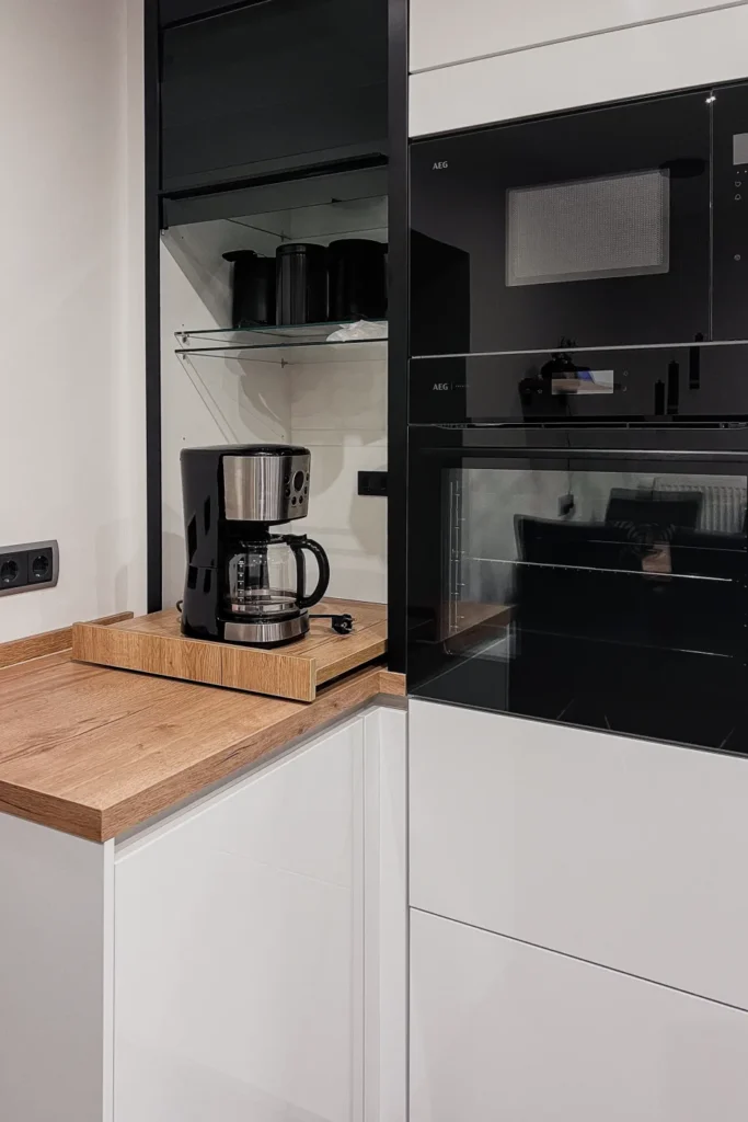 Einbauküche mit Kaffeemaschine auf Arbeitsplatte, daneben Backofen; AEG-Schriftzug am Gerät sichtbar.