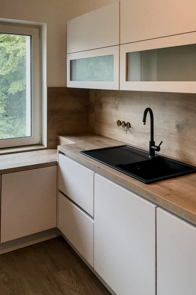 Moderne Küchenzeile mit Einbauherd, Spüle, weißem Unterschrank und Oberschränken mit Nischenblick über Eck