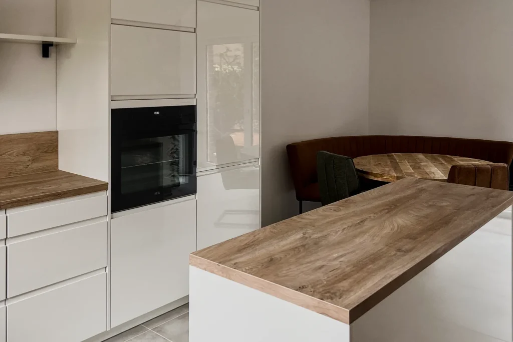 Küchenzeile mit Backofen und Schrankfronten sowie Esstisch in hellem Wohnraum