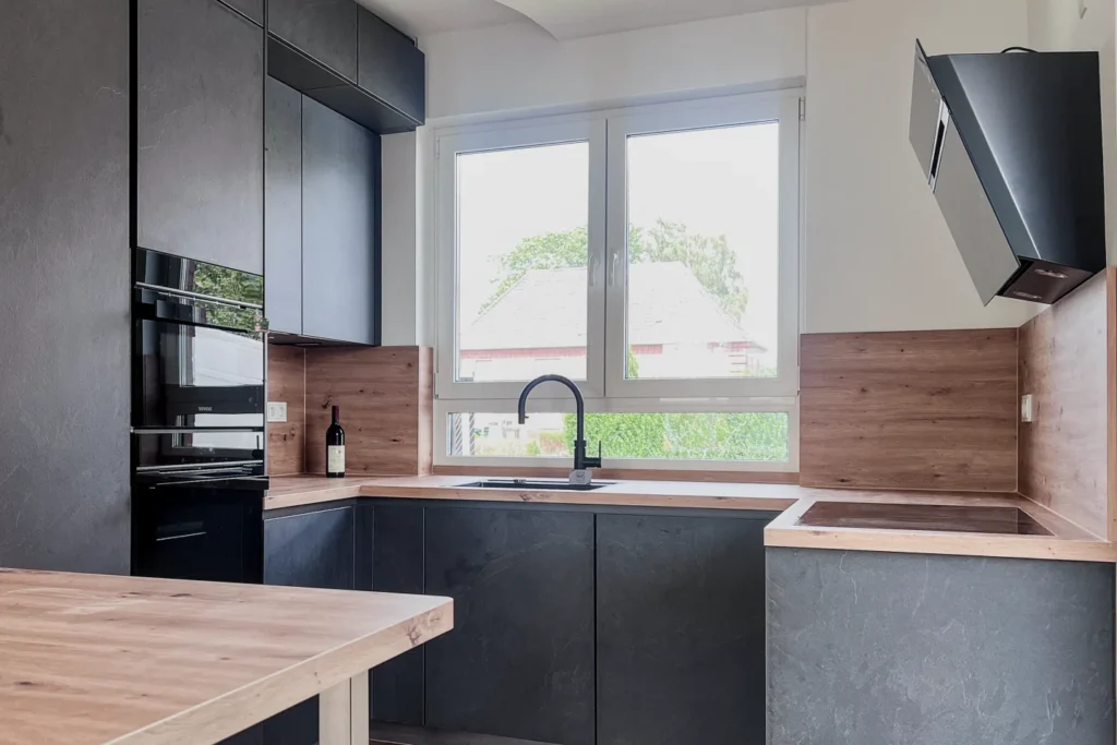 Moderne Küche mit Spüle unter Fenstern, dunklen Unterschränken, Holzfronten, Backofen und Dunstabzugshaube