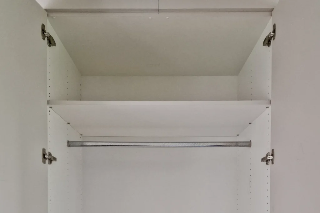 Offener Hängeschrank mit verstellbaren Einlegeböden und Stützstange, weiße Schrankinnenwand.