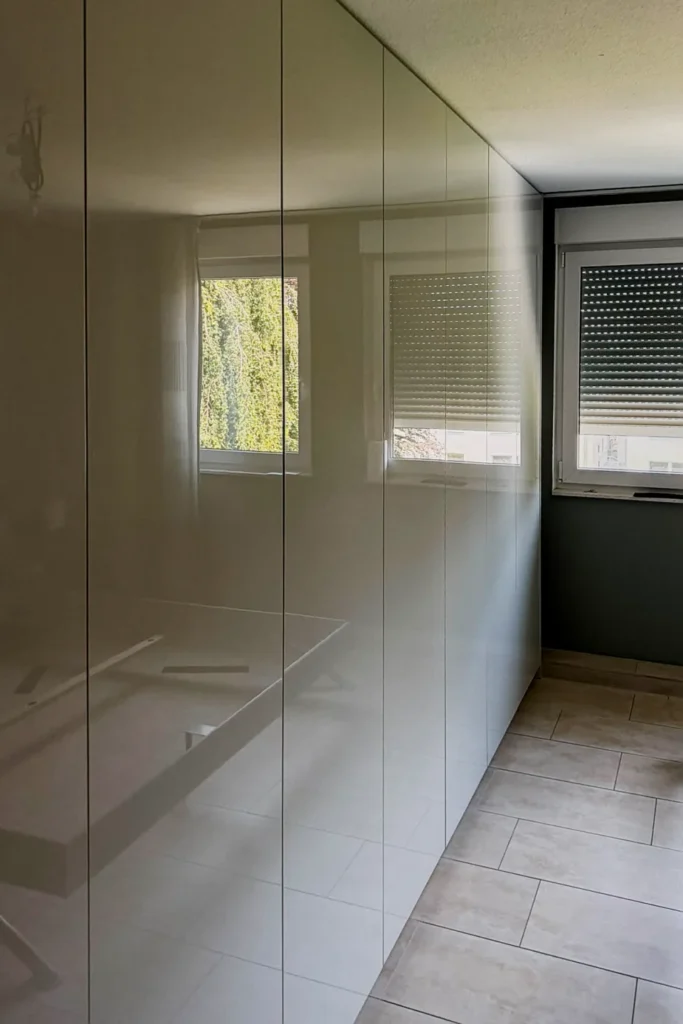 Einbau-Küchenschrank mit glatten Schranktüren, angrenzend Fliesenboden und Fenster mit Rollläden