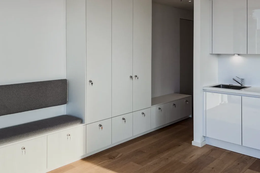Einbauküche mit Spüle, Unterschränken und Hochschrank, daneben Sitzbank mit Schubladen
