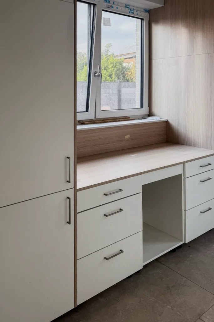 Einbauküche mit Unterschränken, Schubladen und Fensterbank-Sitzbank im hellen Holz-Look