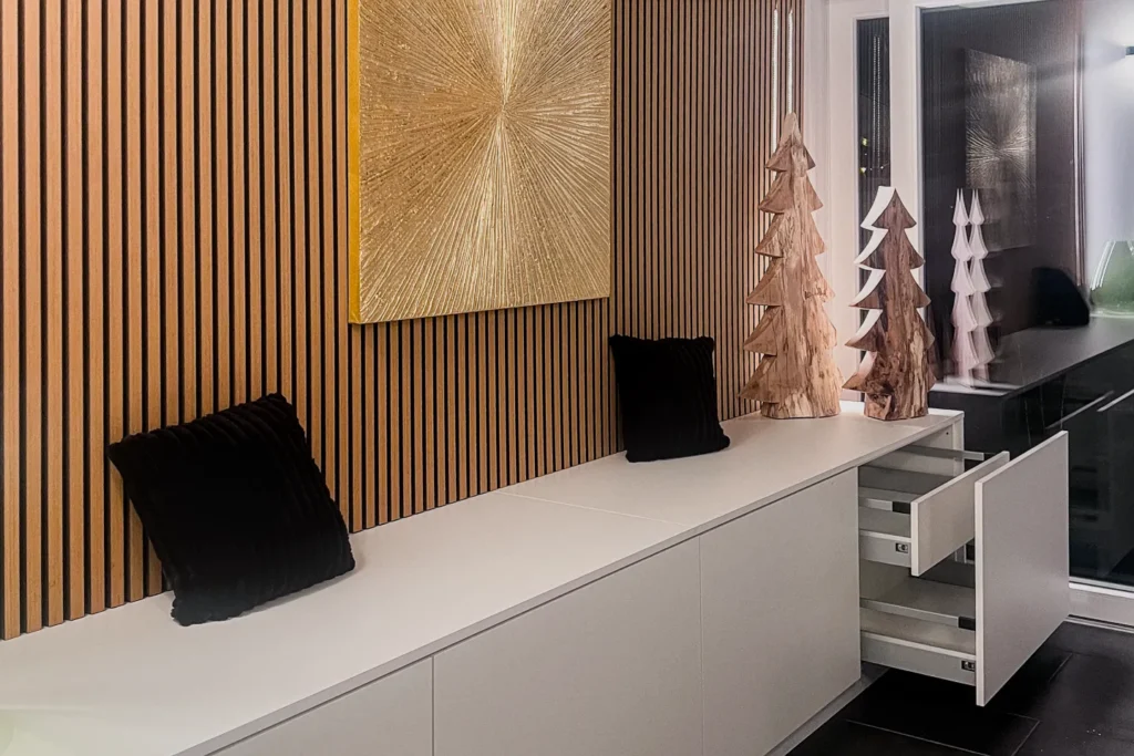 Küchenarbeitsplatte mit Unterbau, Schubladen und dekorativen Holz-Figuren vor einer Holzlamellenwand