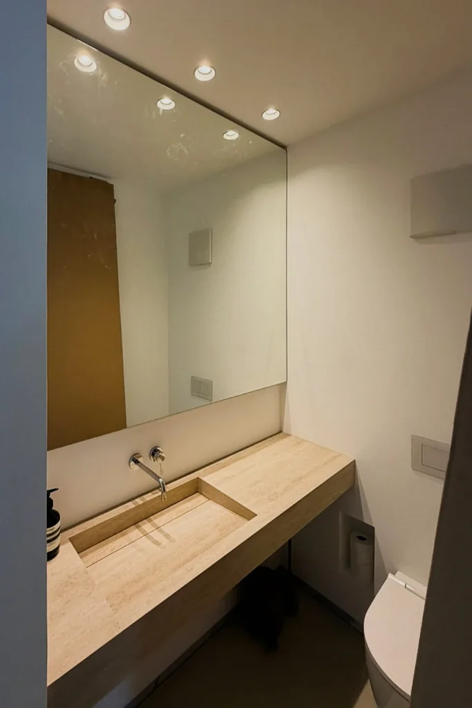 Waschtisch mit eingelassener Spüle, beleuchtetem Spiegel und LED-Spotlights im modernen Bad