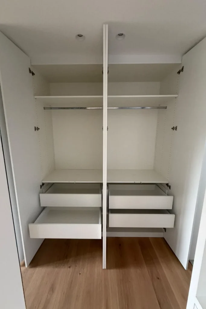Offener Küchenschrank mit Innenregalen und mehreren Schubladen, zentral geteilte Front mit Griffleisten.